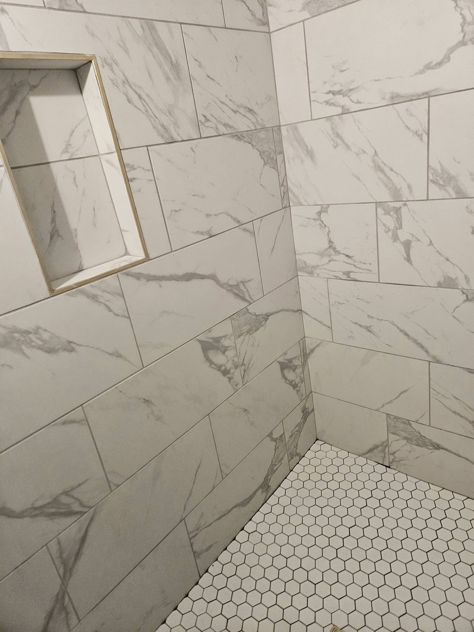 Custom marble-look tile shower with niche shelving installed by Floor Masters of Acadiana.
