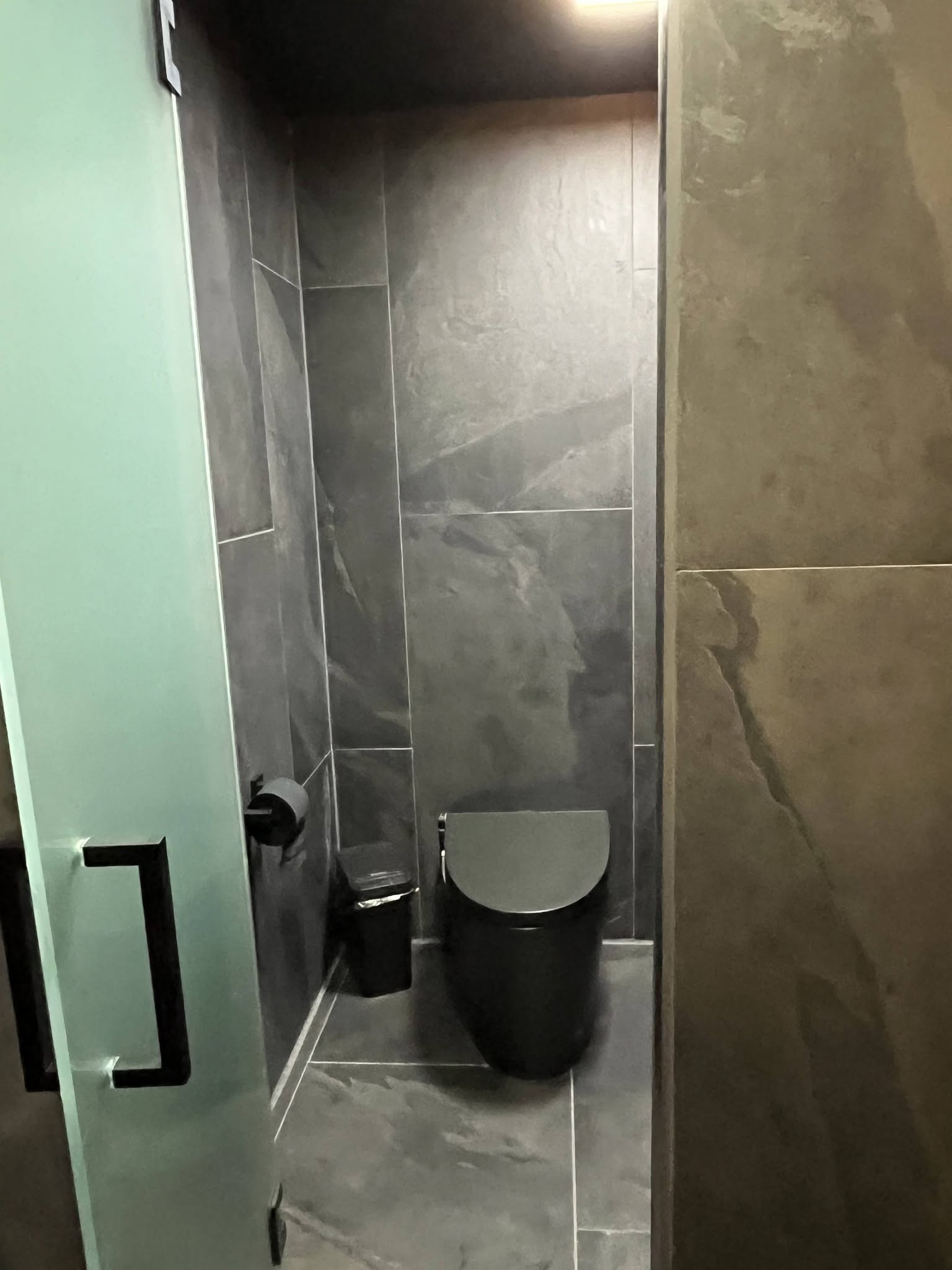 Custom bathroom remodel with large-format porcelain tile and modern wall-mounted toilet by Floor Masters of Acadiana.
